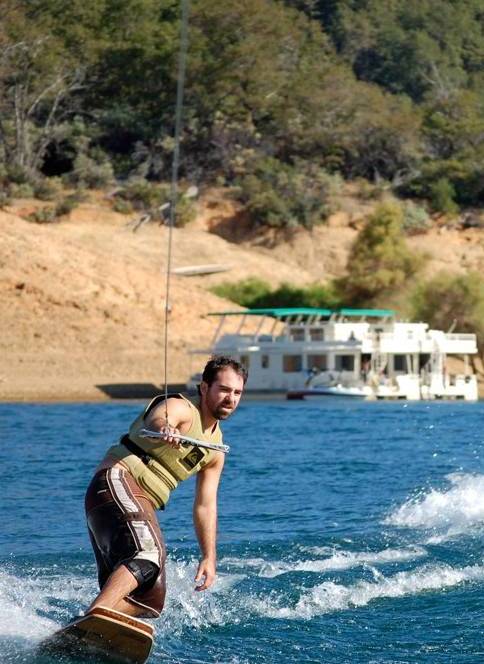 Man wakeboarding with houseboat in the background