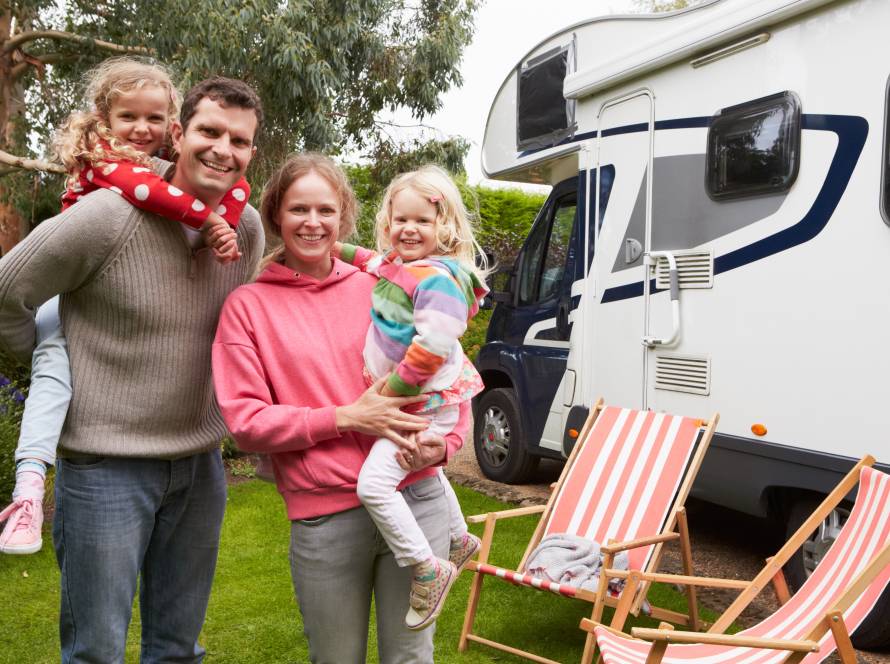 Family of 4 standing by RV in campground