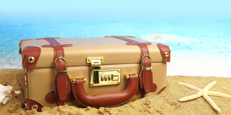 vacation_suitcase on sand beside water