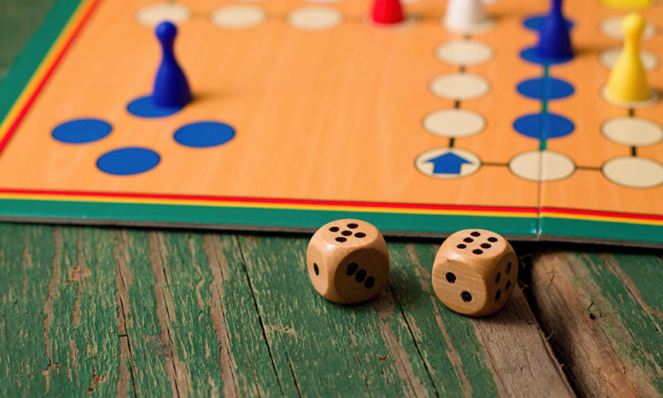 Two wooden dices in front of ludo with figurines