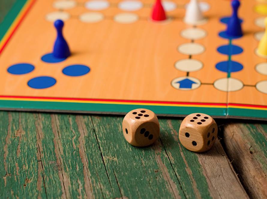 Two wooden dices in front of ludo with figurines
