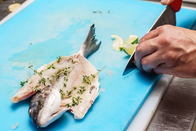 hands prep fish on houseboat counter