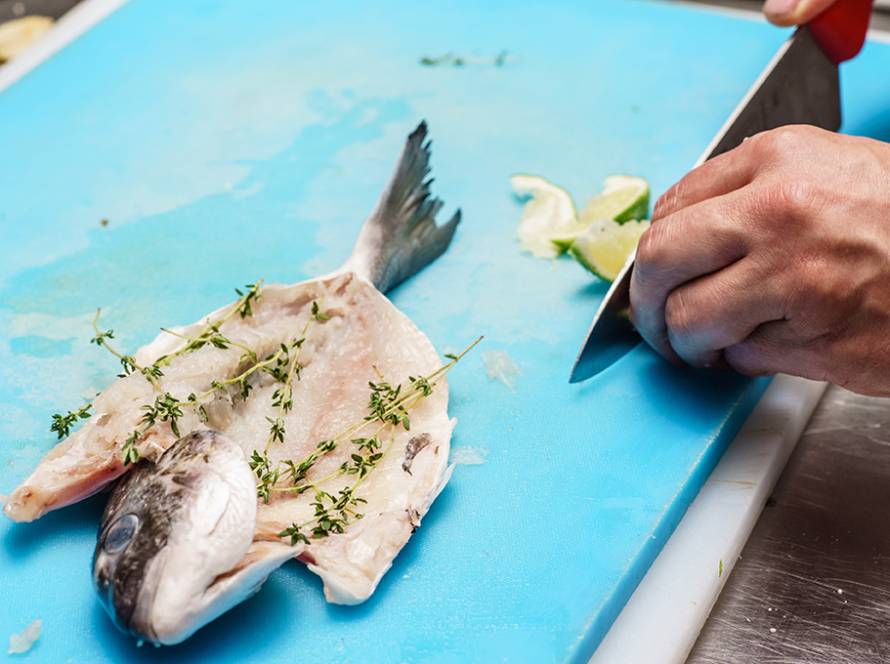 hands prep fish on houseboat counter
