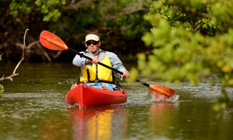 man paddling kayak during houseboat rentals